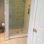Custom tiled shower with glass accent wall, marble tile floor and custom glass door