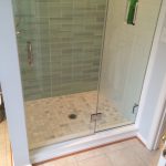 Custom tiled shower with glass accent wall, marble tile floor and custom glass door